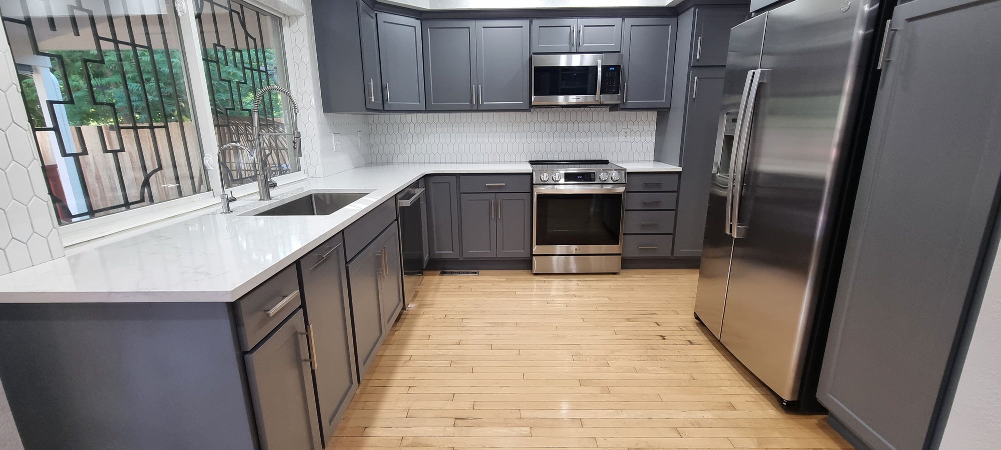 A spotless modern gray kitchen with white quartz counters and stainless steel appliances after a deep cleaning in Denver